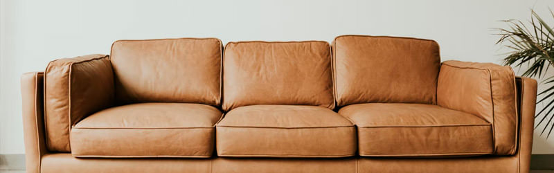 A foto mostra um sofá de três lugares produzido em couro com a elegância do tom
    marrom-claro.