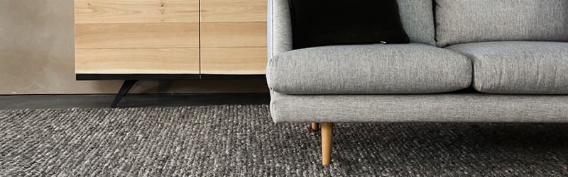 salar de estar com carpete cinza e sofá cinza claro e pés de madeira